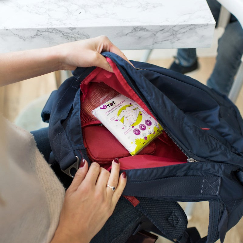 Mother putting disposable bib in a diaper bag