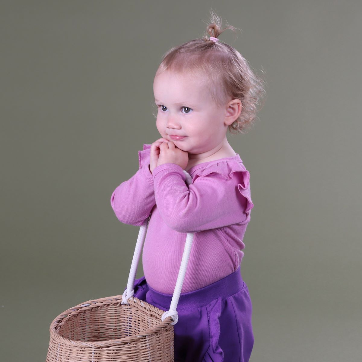 Baby wearing Orchid Merino frill bodysuit pairing it with purple pant