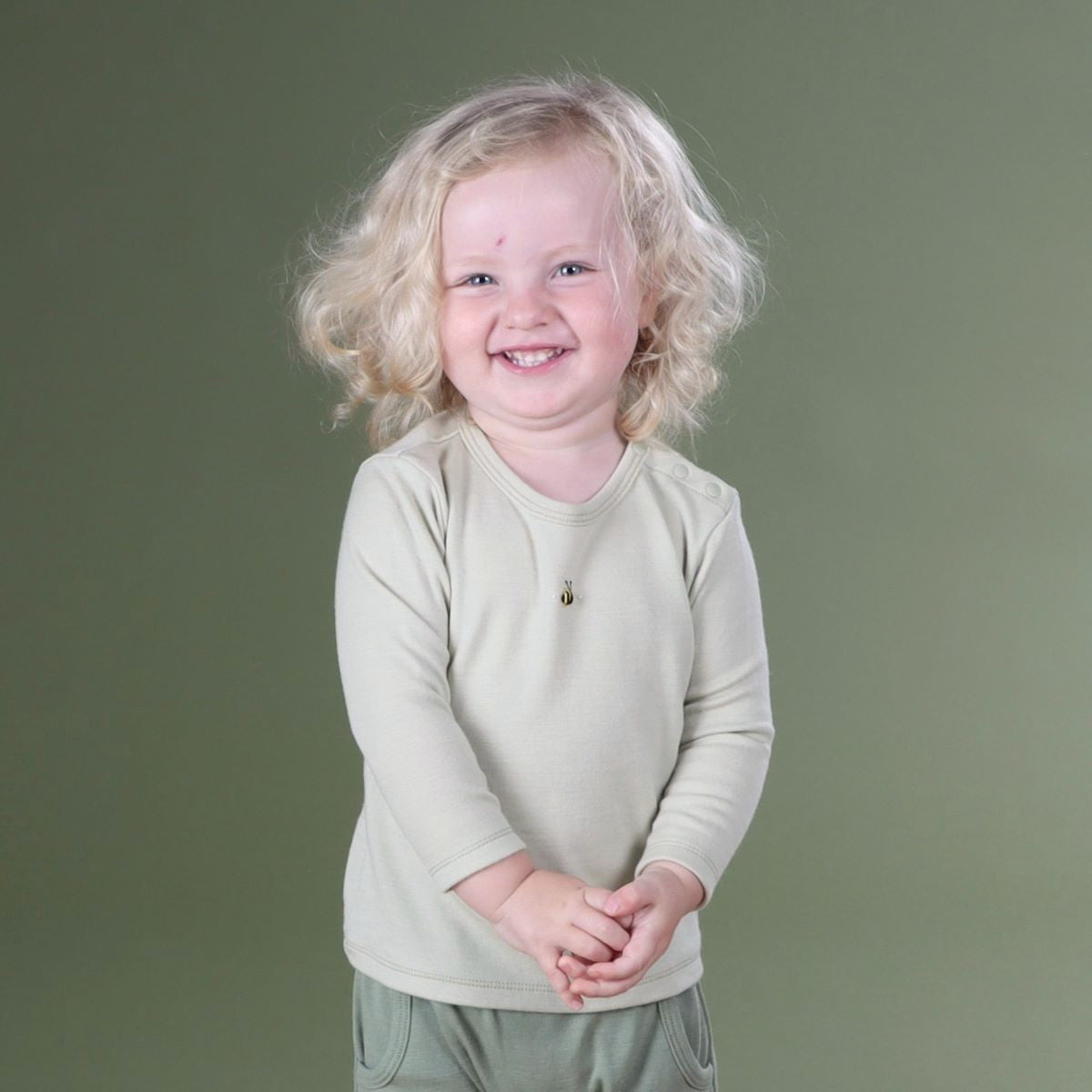 Happy baby wearing Cosy Dreams Merino long sleeve top in tea green bee from Dimples New Zealand