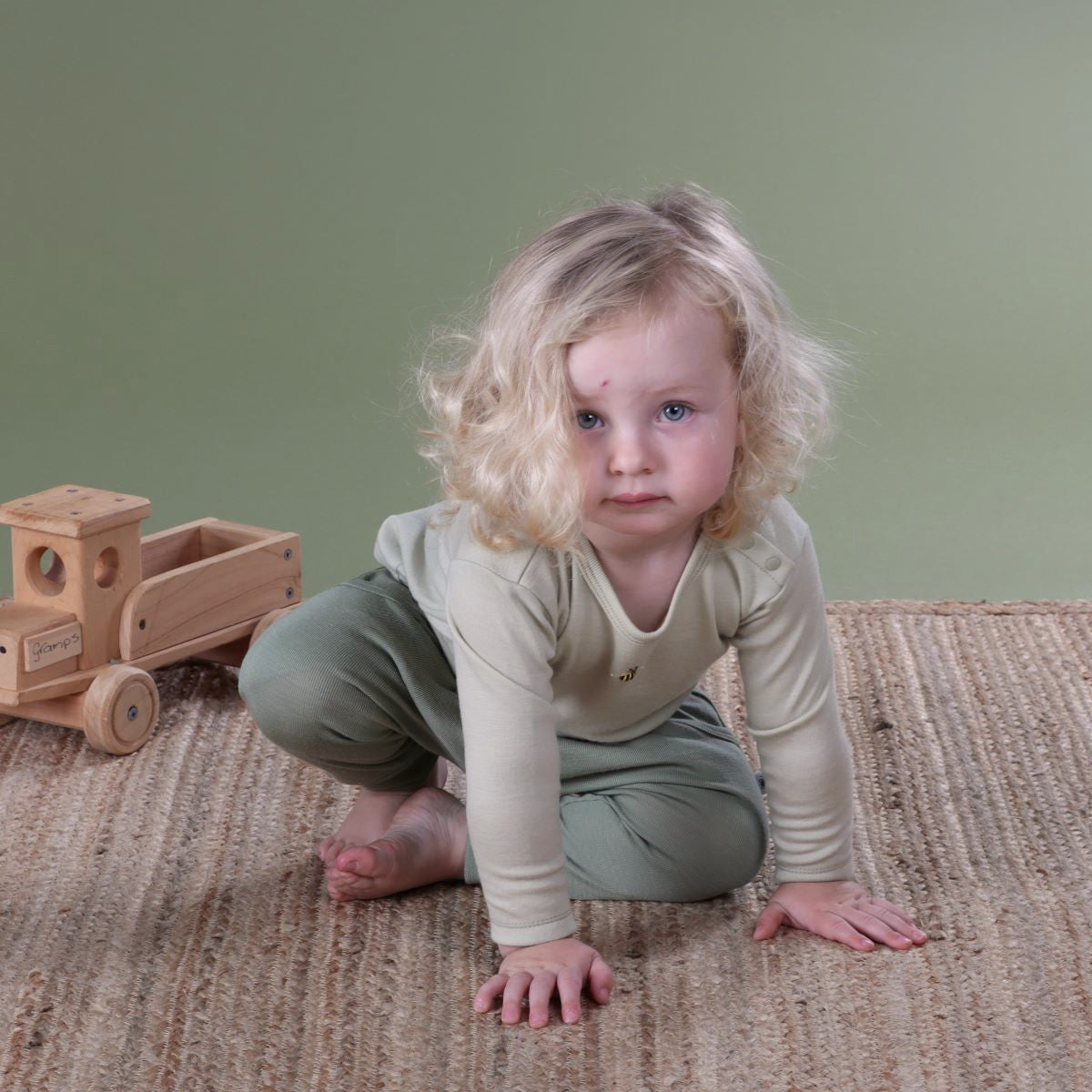 Baby wearing Cosy Dreams Merino long sleeve top in tea green bee pairing it with moss pants from Dimples New Zealand