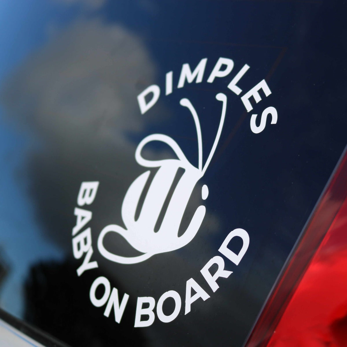 Dimples by Jane Anne Baby on Board Sticker on red car zoomed in