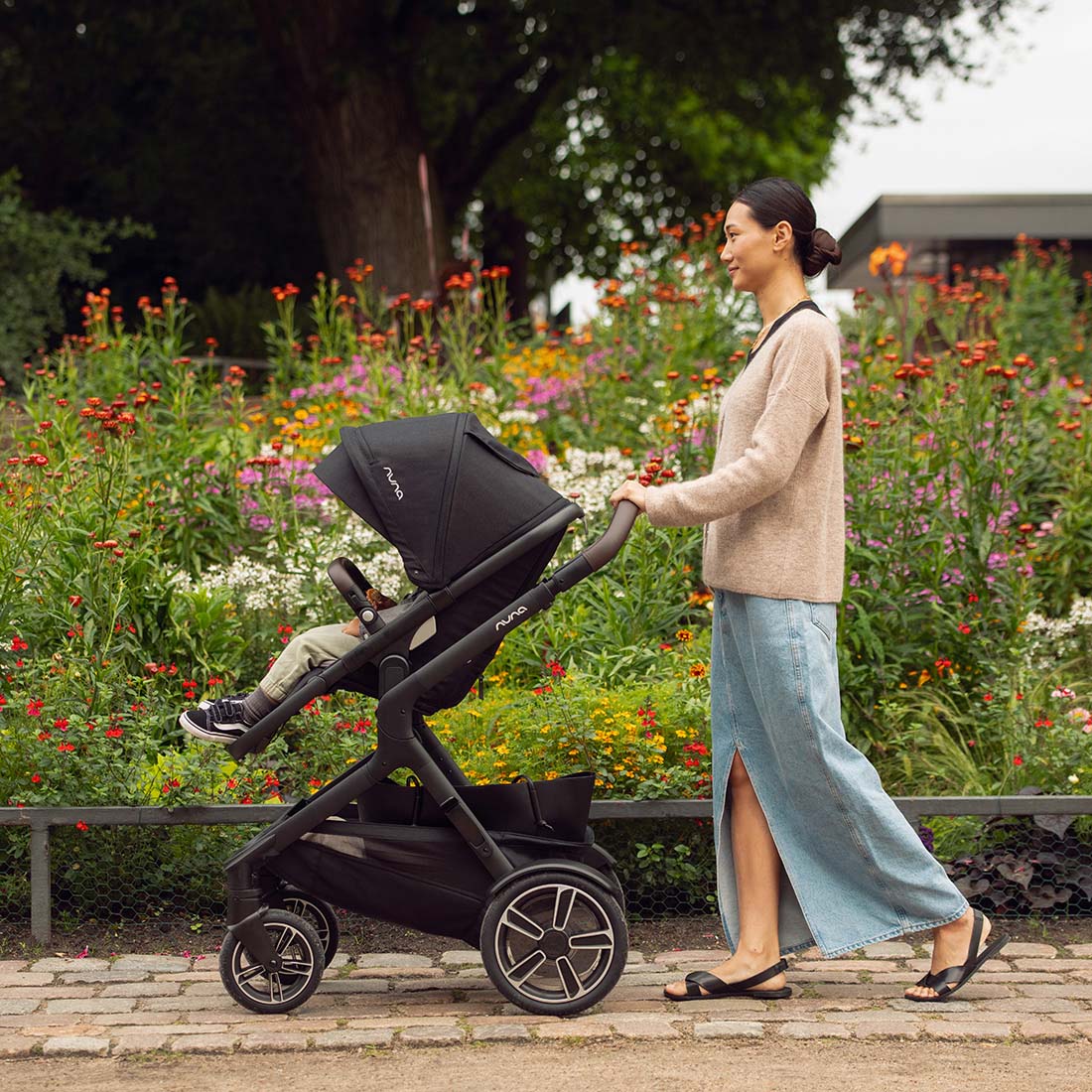 Mother walking in a garden with Demi Next Stroller