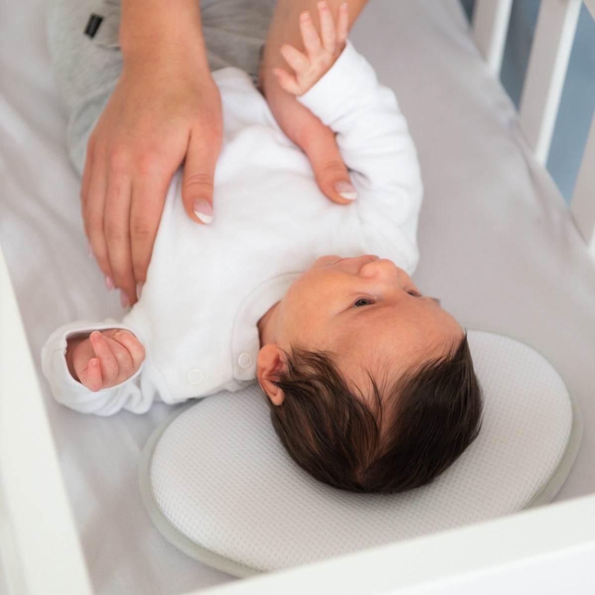 Baby putting boy to sleep in a cot with baby pillow from doomoo