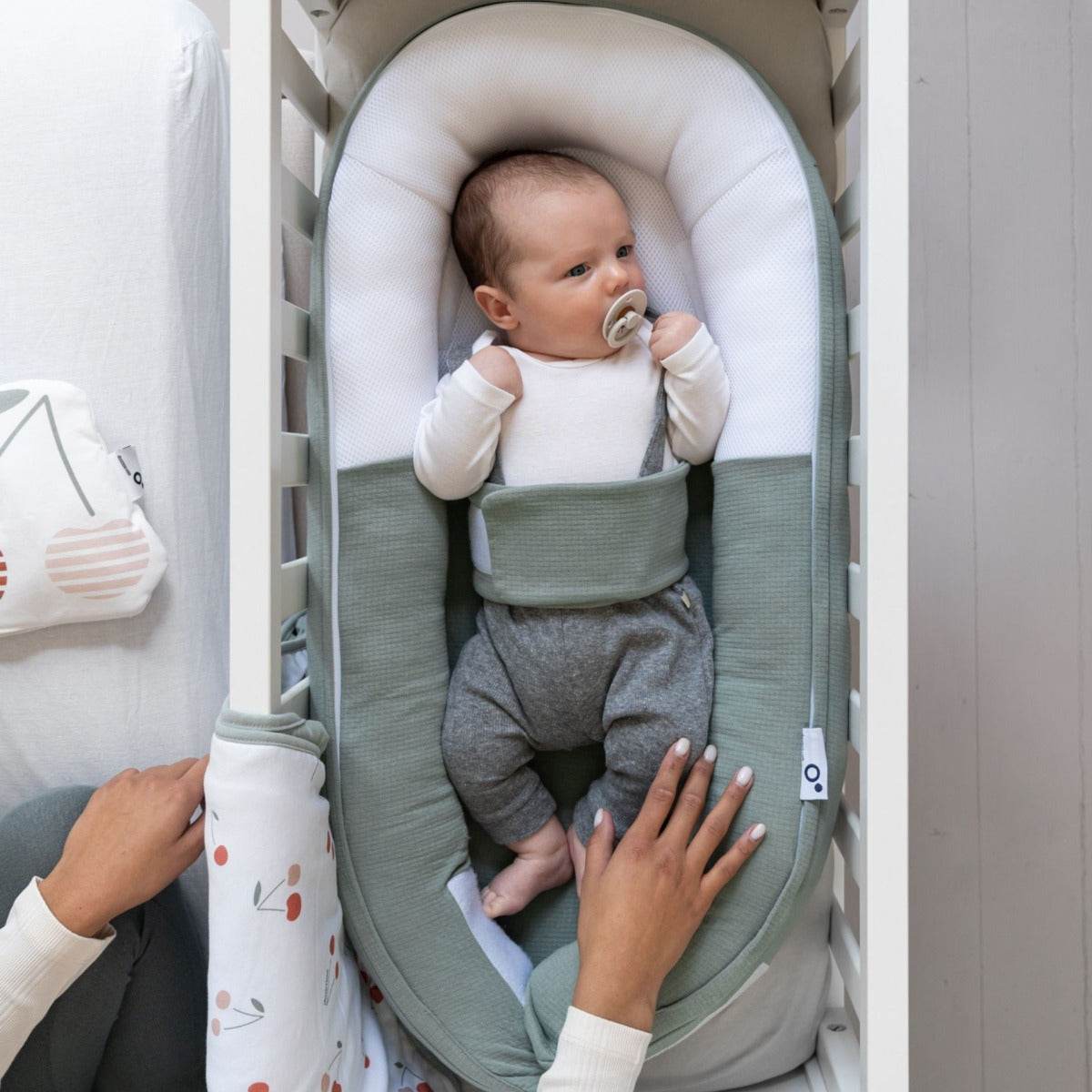 Baby laying in Doo Moo Cocoon nest in Tetra Jersey Green in cot