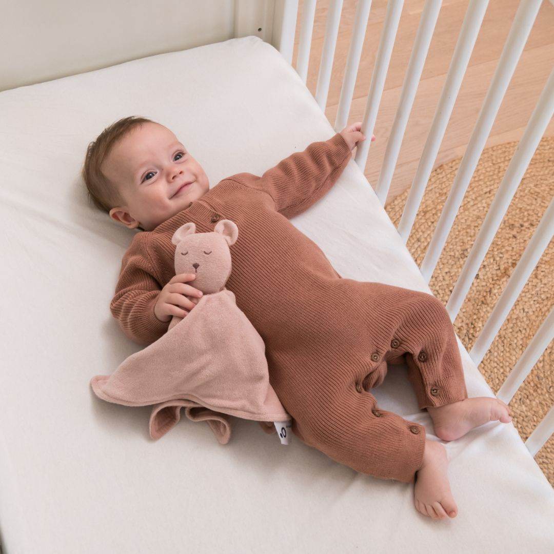 Baby playing in cot with doomoo bunny detachable baby soother in pink