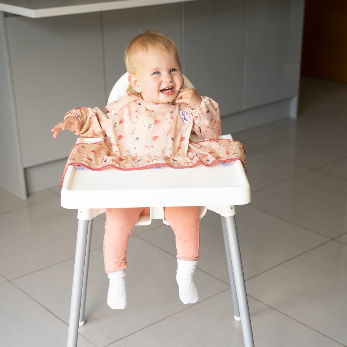 Happy baby sitting on a highchair wearing long sleeve bib with fox print