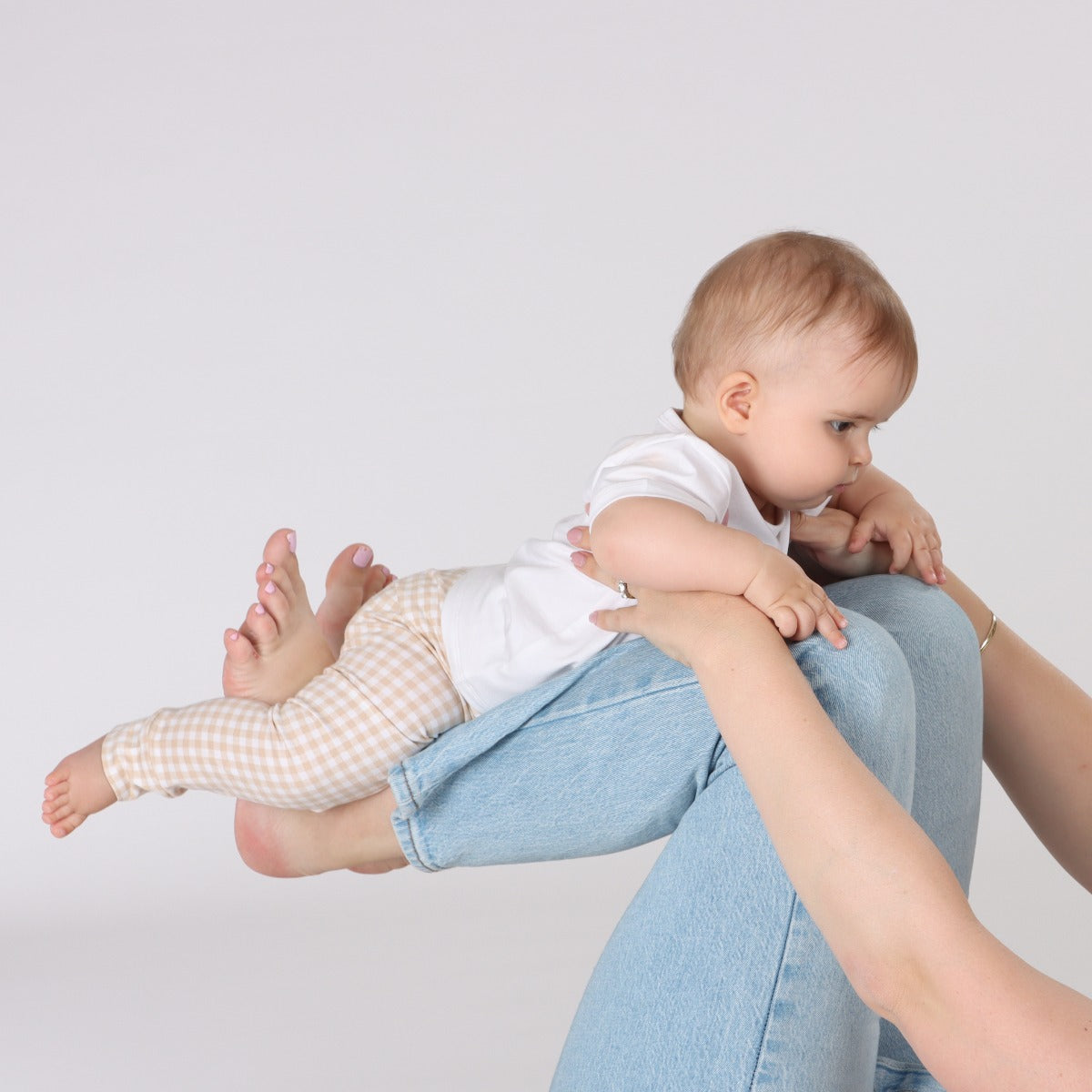 Baby wearing Organic cotton leggings in gingham pattern playing with mother