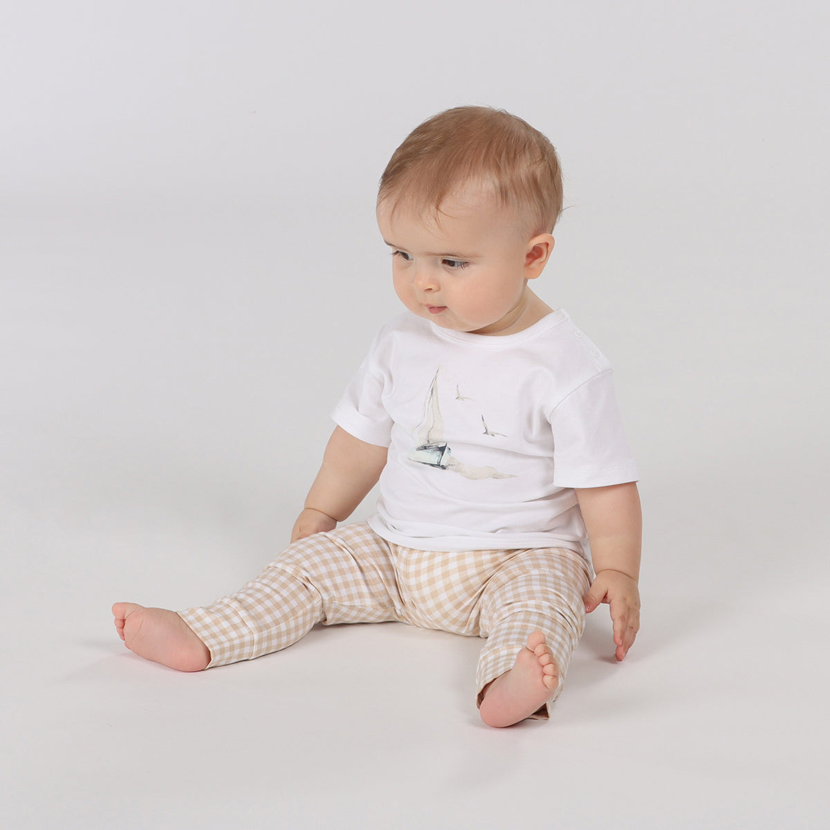 Baby wearing organic cotton leggings in gingham pattern pairing it with cotton t-shirt