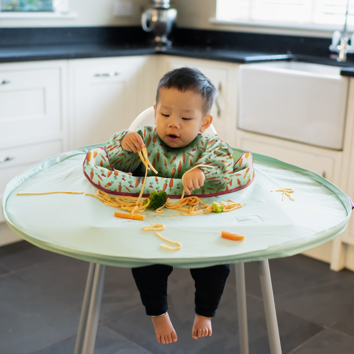 Baby eating with Tidy Tot tray around highchair and long sleeve carrots bib