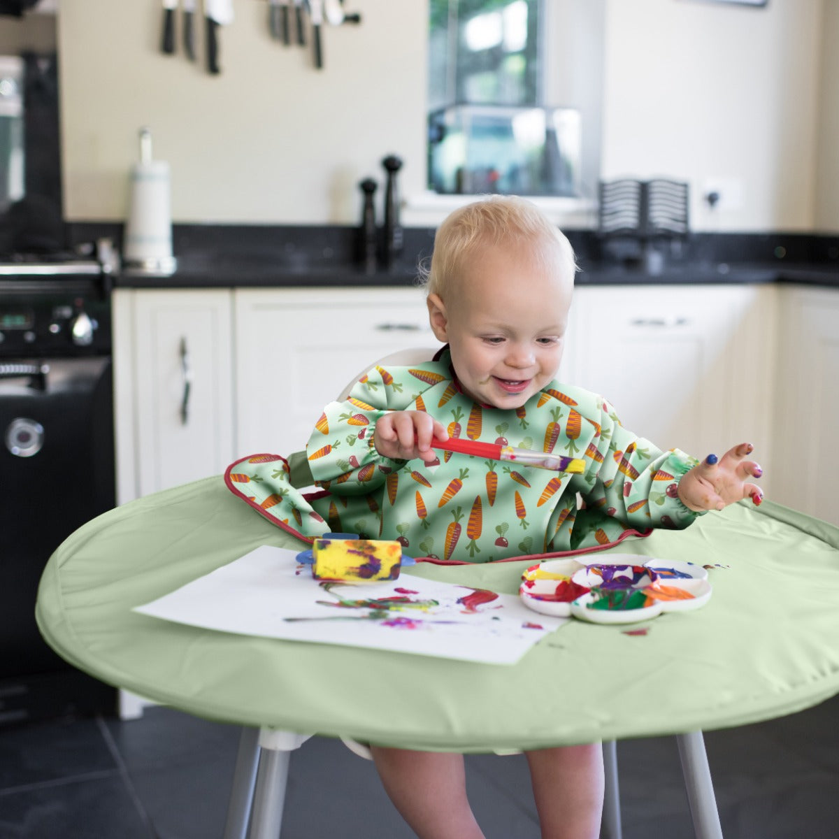 Baby playing with colors with Tidy Tot tray around highchair and long sleeve carrots bib