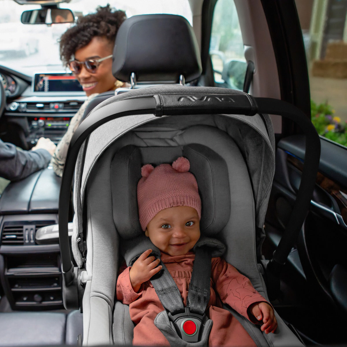 Nuna Pipa Next car seat capsule in granite inside car with happy kid and family