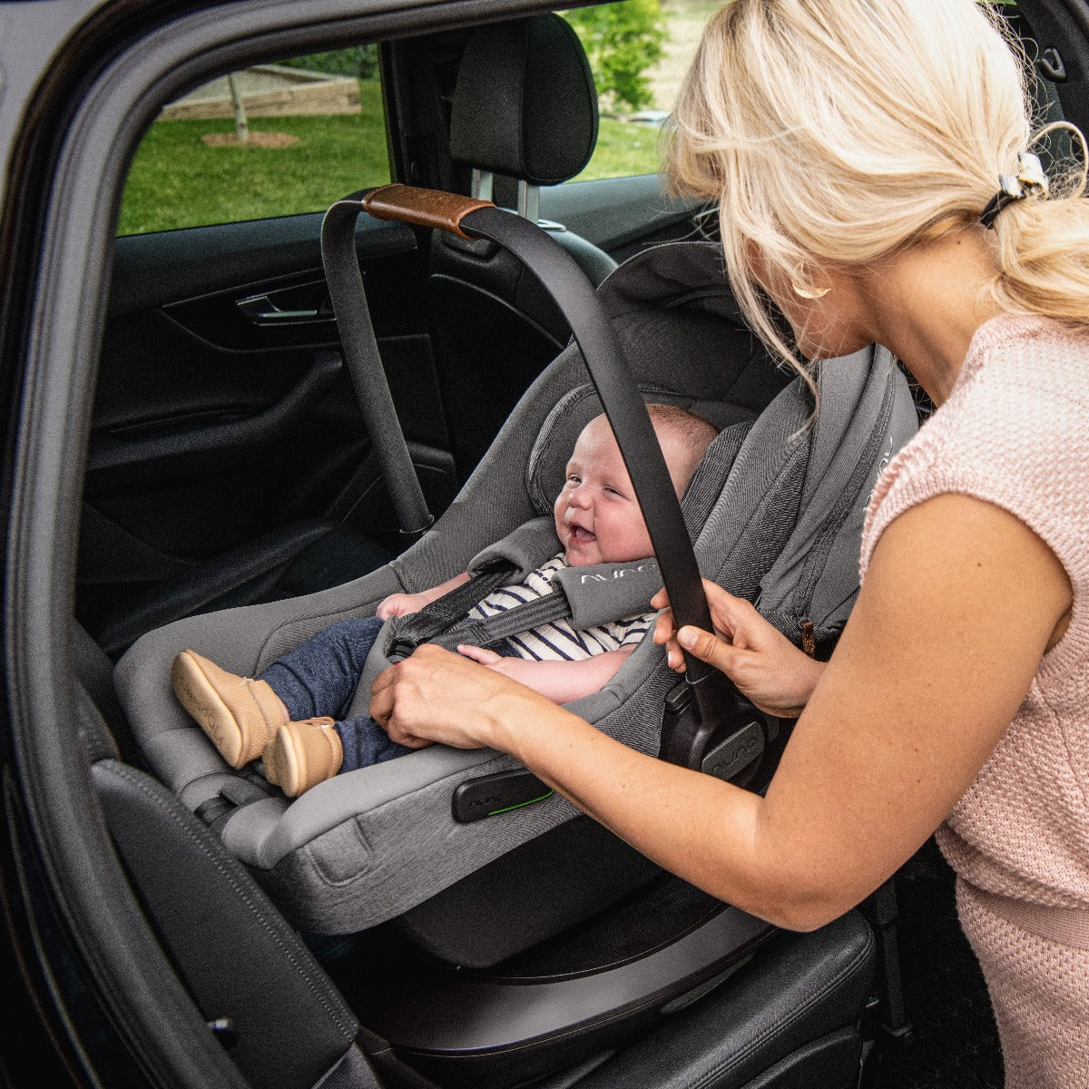 Nuna Pipa Next car seat capsule in Caviar with happy baby inside car
