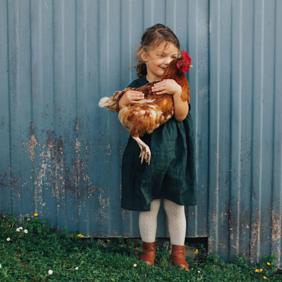 Baby girl wearing Oatmeal Baby and Child Merino Wool Knit Cable Tights from Lamington  and holding hen