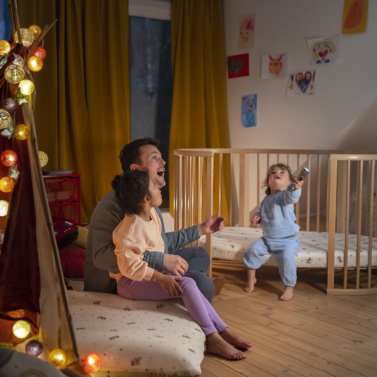 Stokke Mickey jetkids cloud sleeper in a kids room inside tent with lights and father and 2 kids enjoying the space