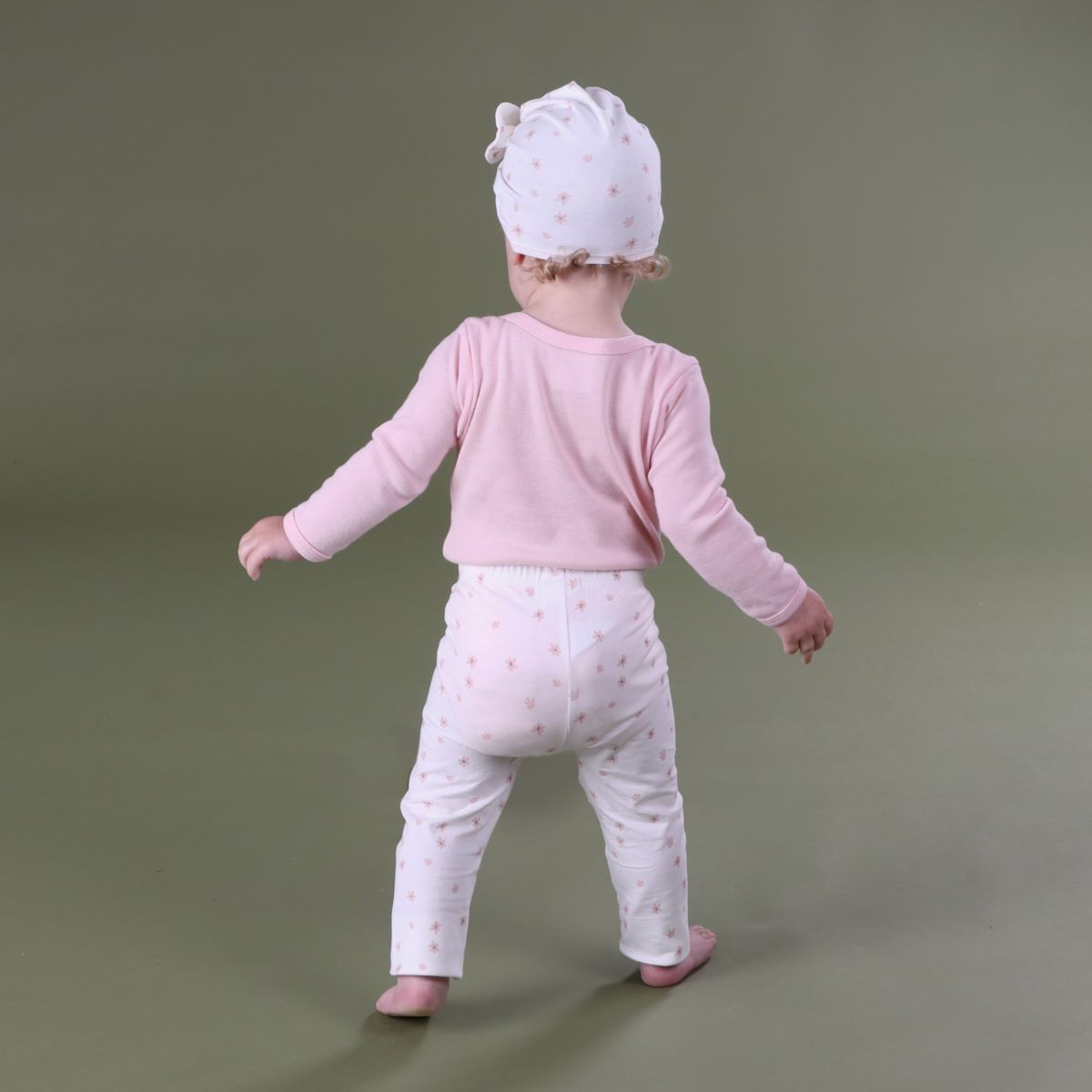 Baby girl wearing dainty floral cotton legging with merino long sleeve top and cotton beanie