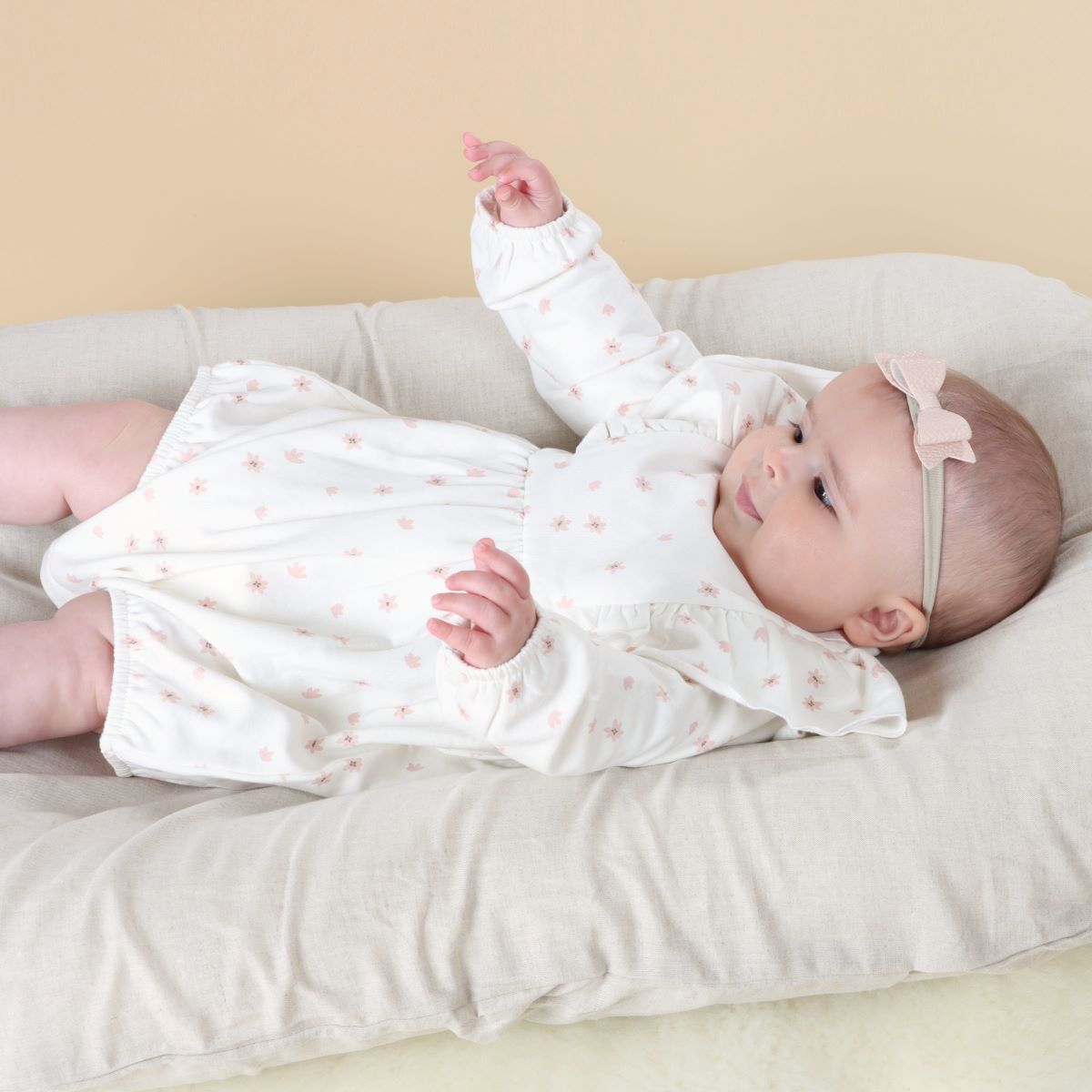 Baby girl playing in a lounger wearing cotton fleece frill baby romper with floral print and pairing it with head band