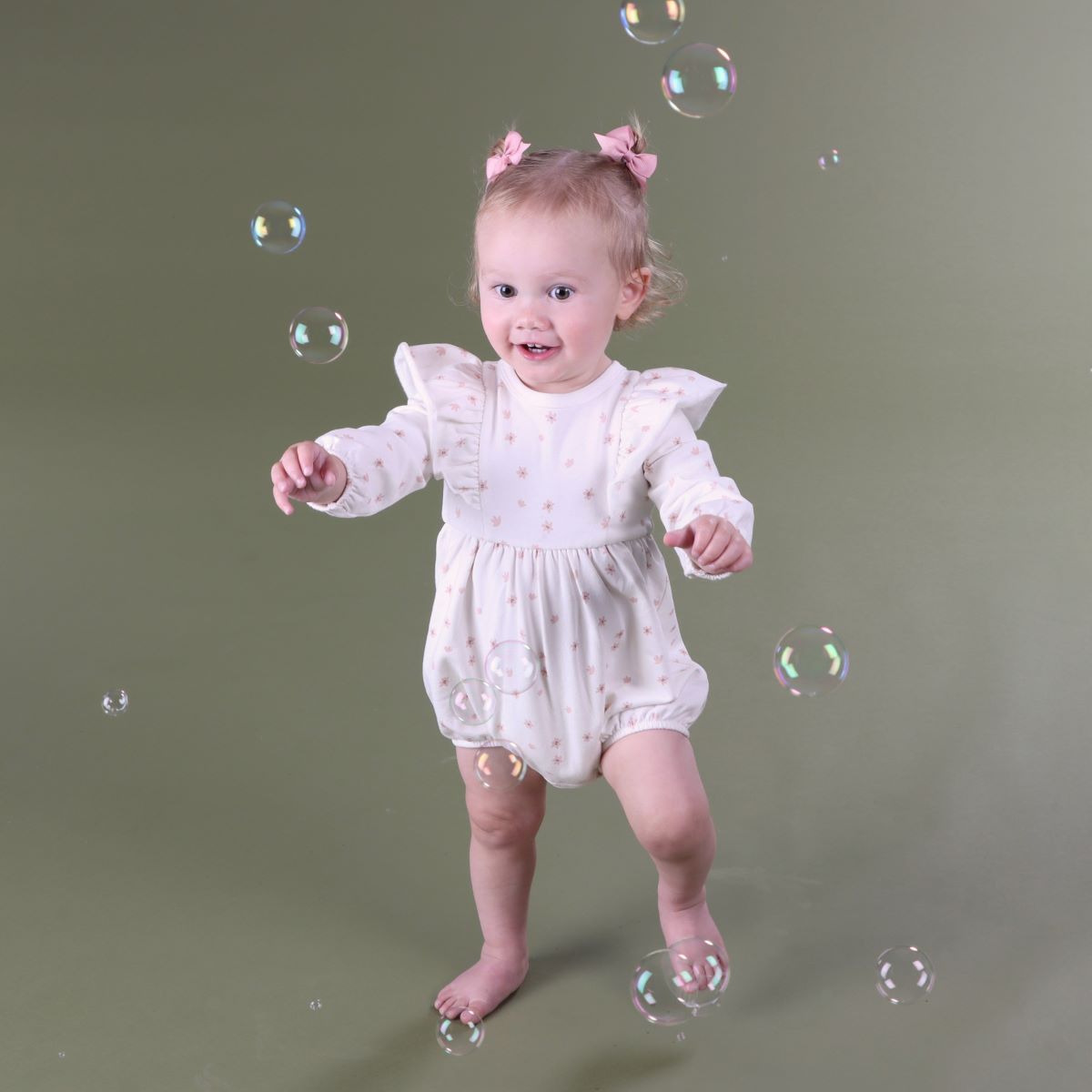 Baby girl playingplaying with bubbles wearing cotton fleece frill baby romper with floral print