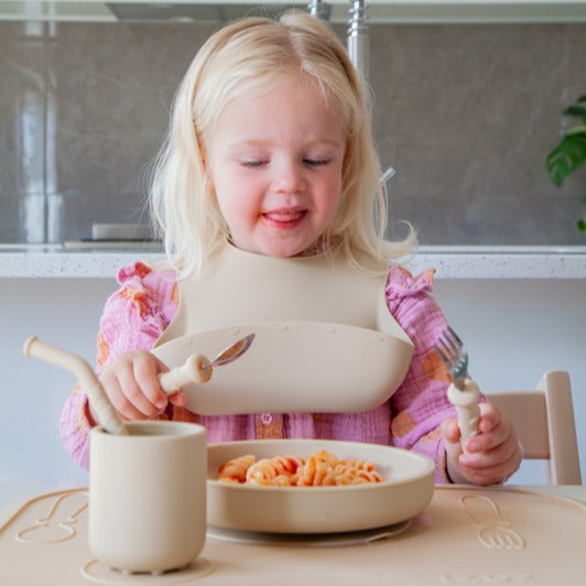 Baby girl eating from silicone plate with cutlery and cup from Zazi