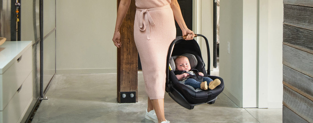 Mother walking in a lobby holding baby in a car capsule