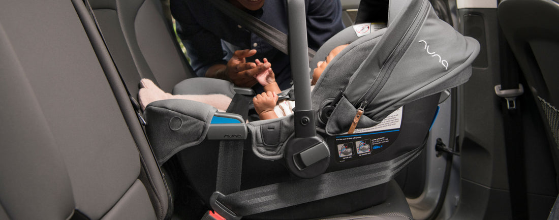 Baby in a Nuna Capsule installed in a car seat with rear facing. 