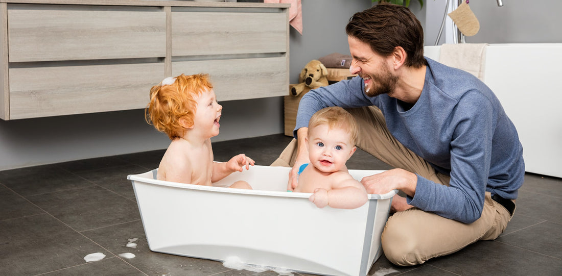 Father sitting and 2 kids enjoying bath time in Stokke Flexi Bath 