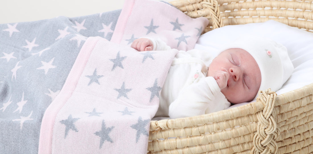 Baby sleeping in a mosses basket wearing Dimples merino beanie and babygrow.