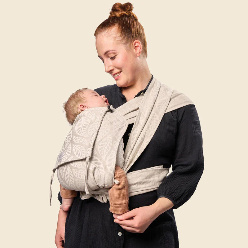 Mother carrying baby in Stokke Limas Carrier plus in valerian beige side carrying.