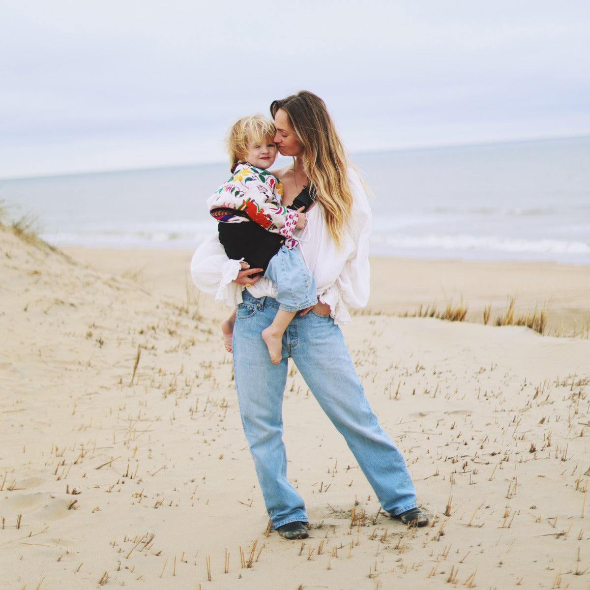Mother carring baby in Wildride Toddler Carrier on a beach