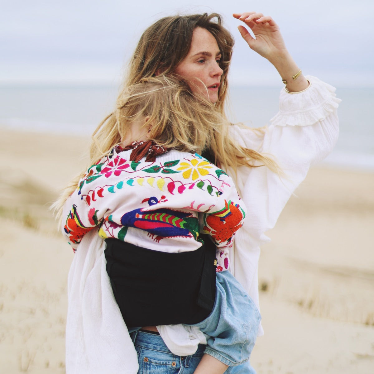 Mother carring baby in Wildride Toddler Carrier on a beach