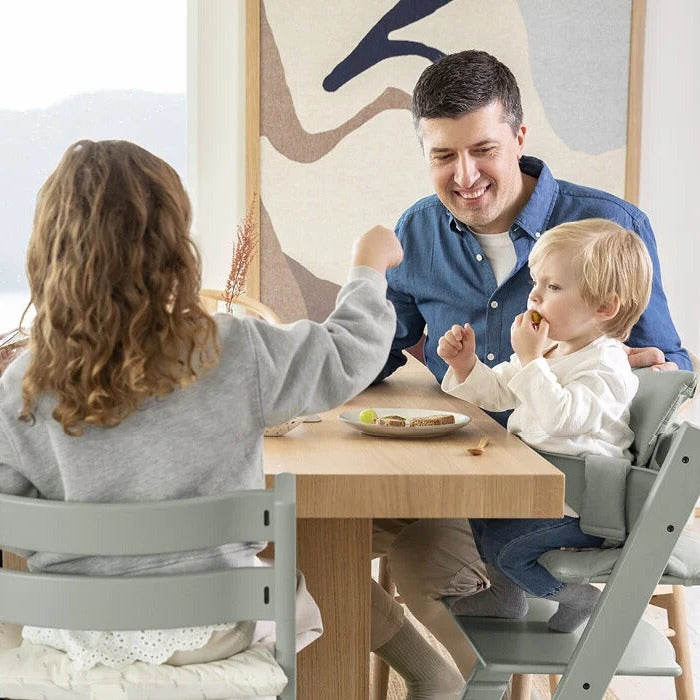 Father feeding baby in Stokke Tripp Trapp Highchair in dinning room