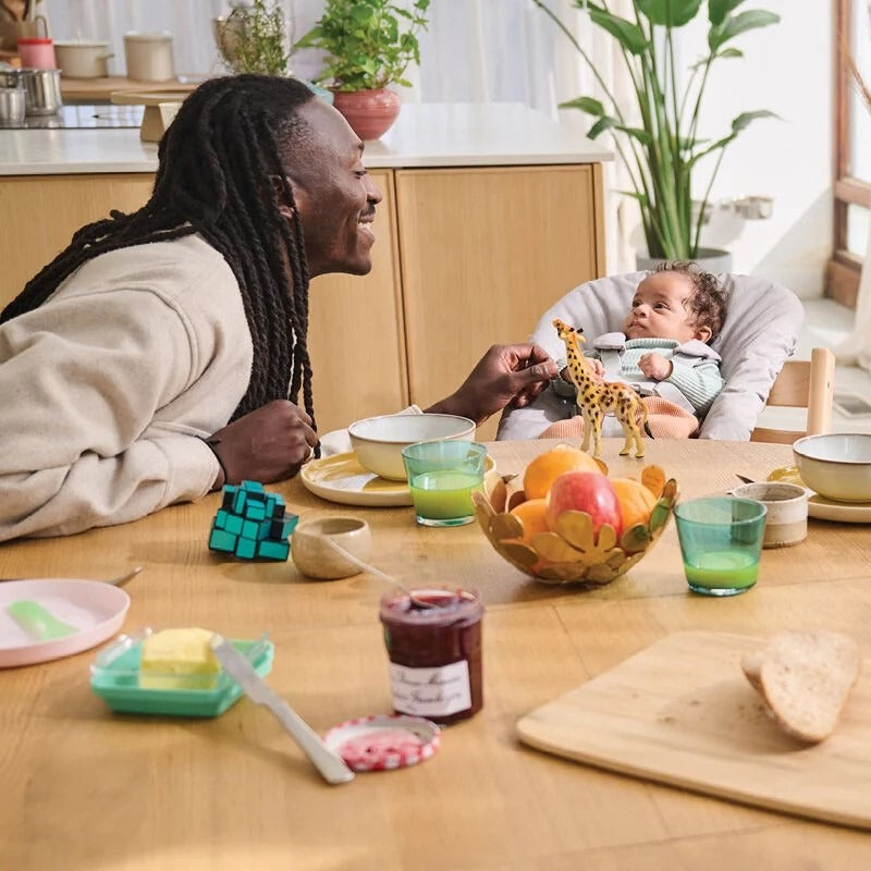 Father feeding baby in Stokke Tripp Trapp Highchair in dinning room