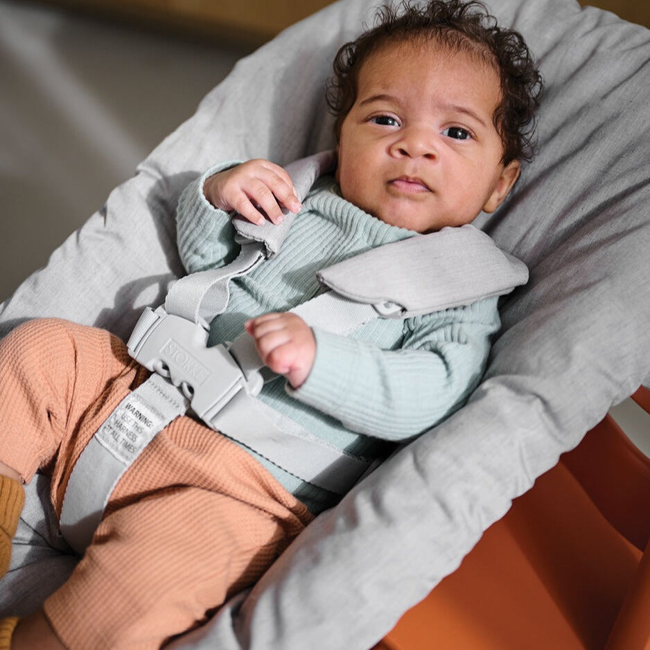 Baby in newborn set on Terracotta Stokke Tripp Trapp Highchair