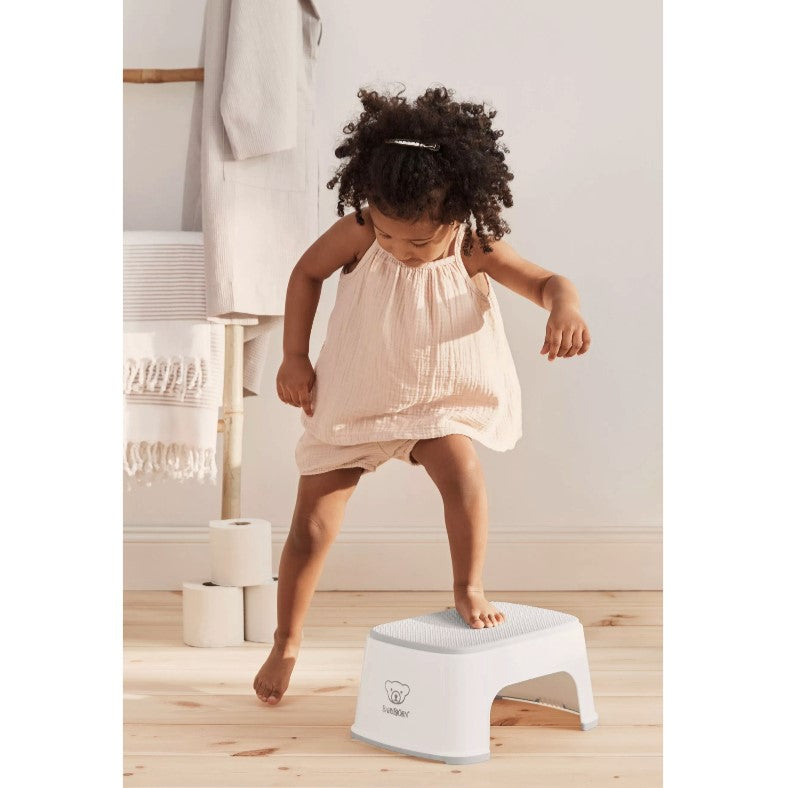 Baby girl stepping on a Babybjorn White Step Stool