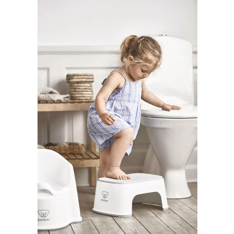 Baby girl stepping on a Babybjorn White Step Stool