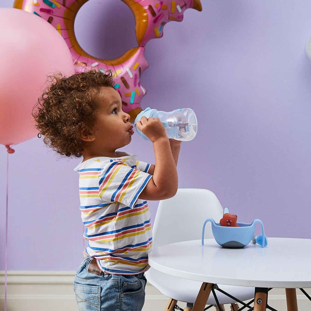 Baby boy standing and drinking water from B.Box Bubble gum sippy cup