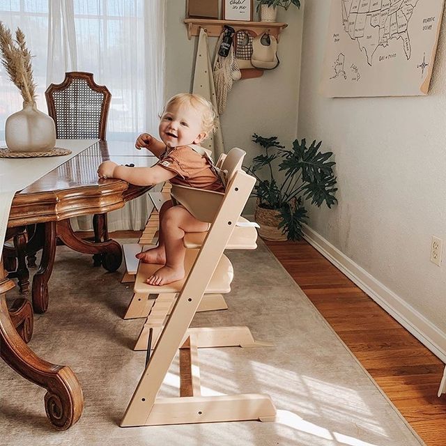 Baby happily sitting in Stokke tripp trapp babyset in natural colour with safety harness at the dinning table