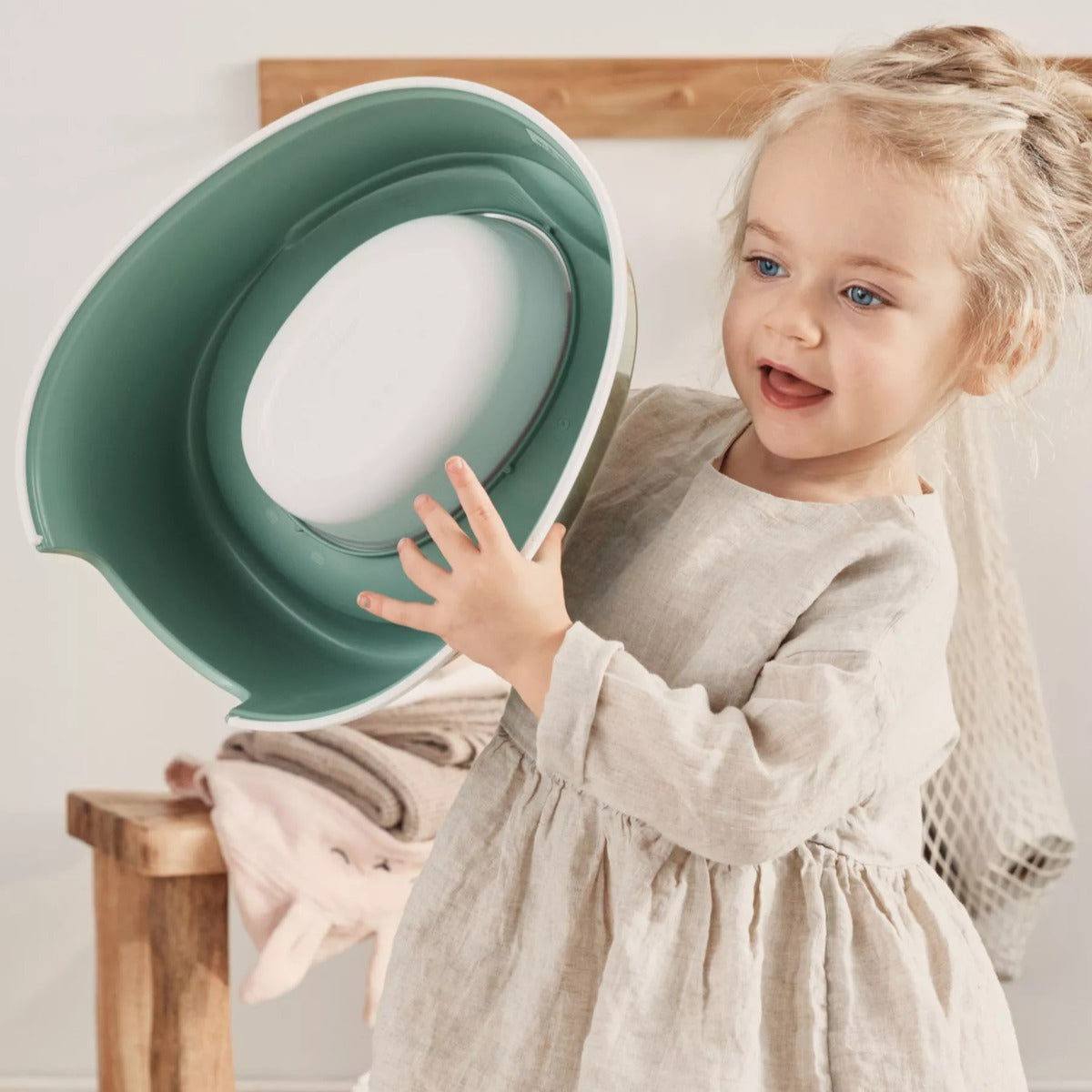 Baby girl holding Babybjorn Smart Potty in green