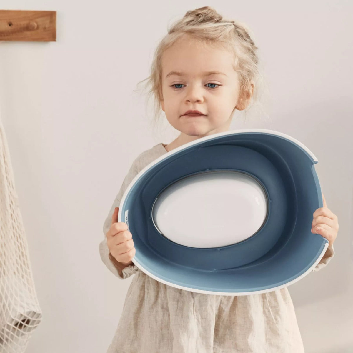 Baby girl holding a Babybjorn Blue Smart Potty seat