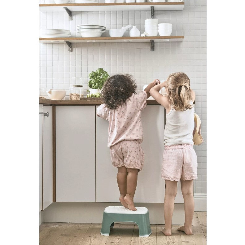 Kid standing on the Babybjorn Deep green Step Stool to reach kitchen top