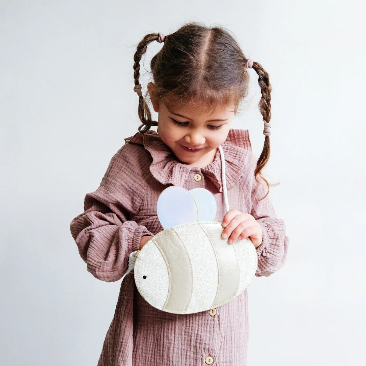 Girl checking out her Bee shaped bag with glitter attached to strap
