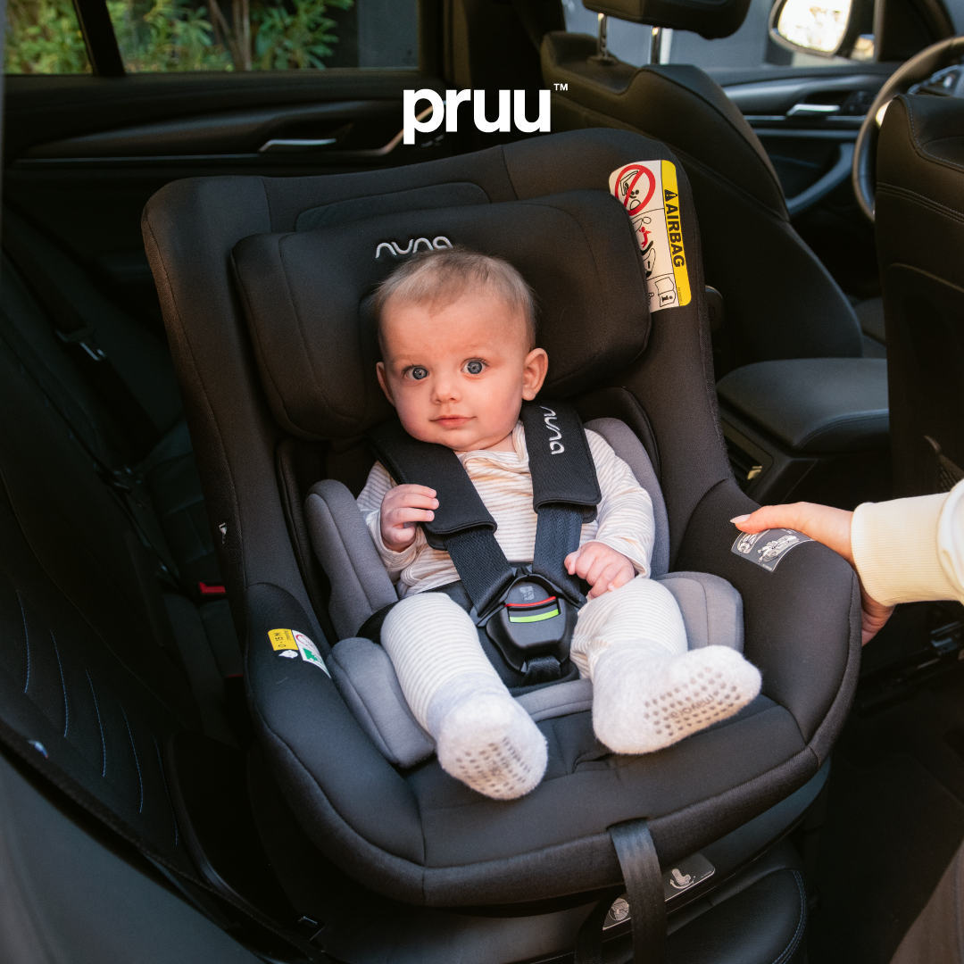Baby boy sitting in a Pruu car seat in car back seat