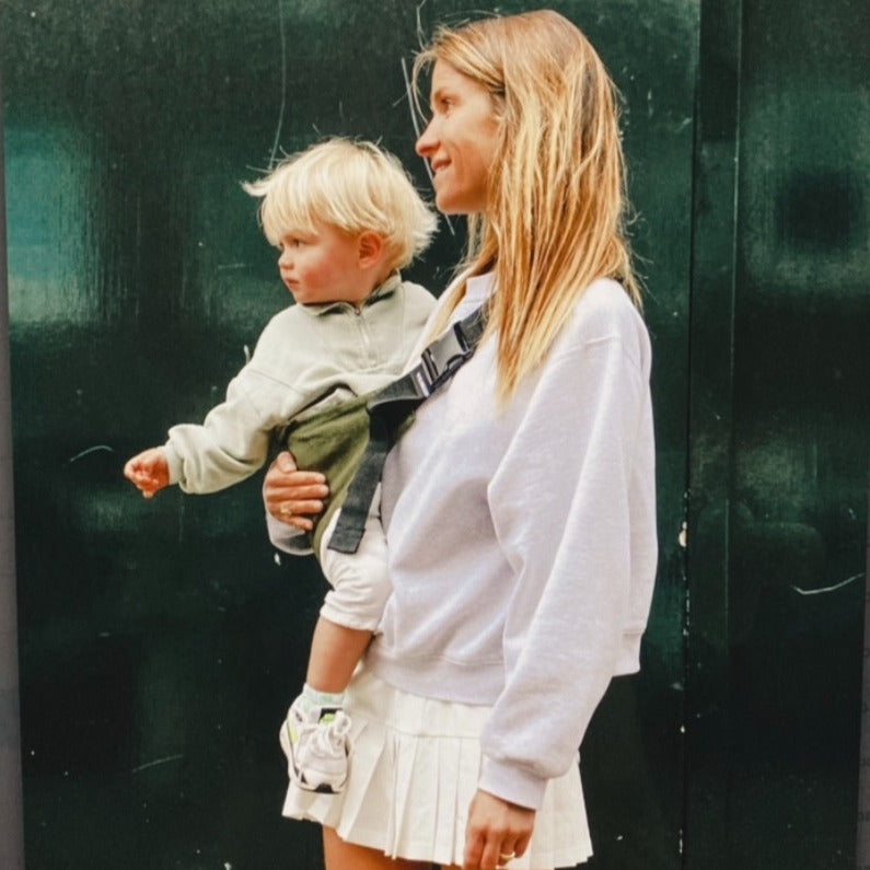 Mother carrying baby boy siwth Wildride Toddler Carrier in Army Green