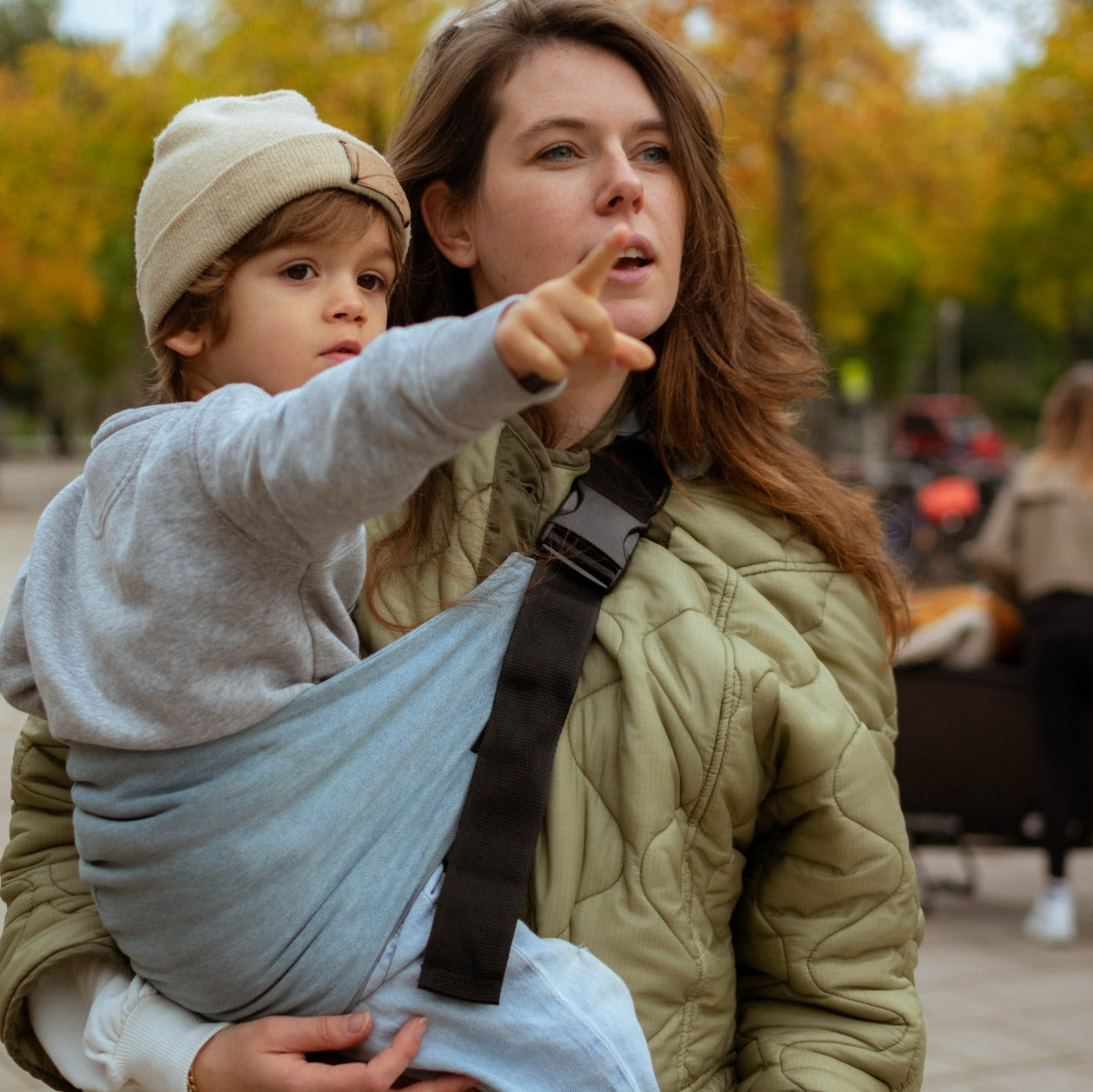 Mother carrying baby with Wildride Toddler Carrier in Denim walking in a park