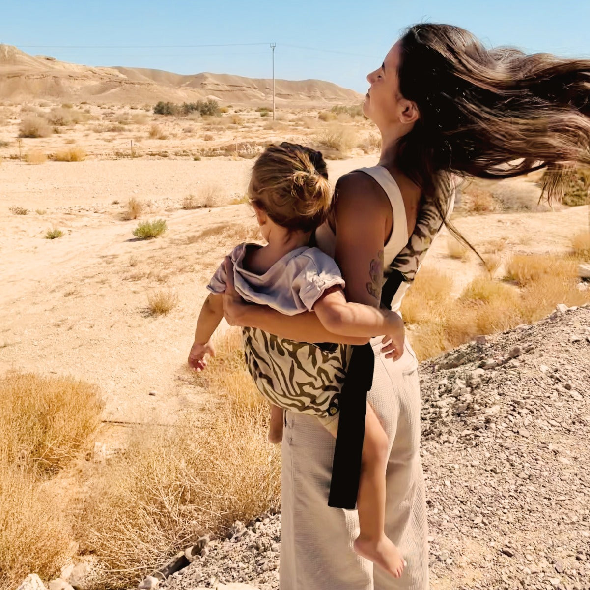 Mother carrying toddler in Wildride Toddler Carrier in Zebra Print