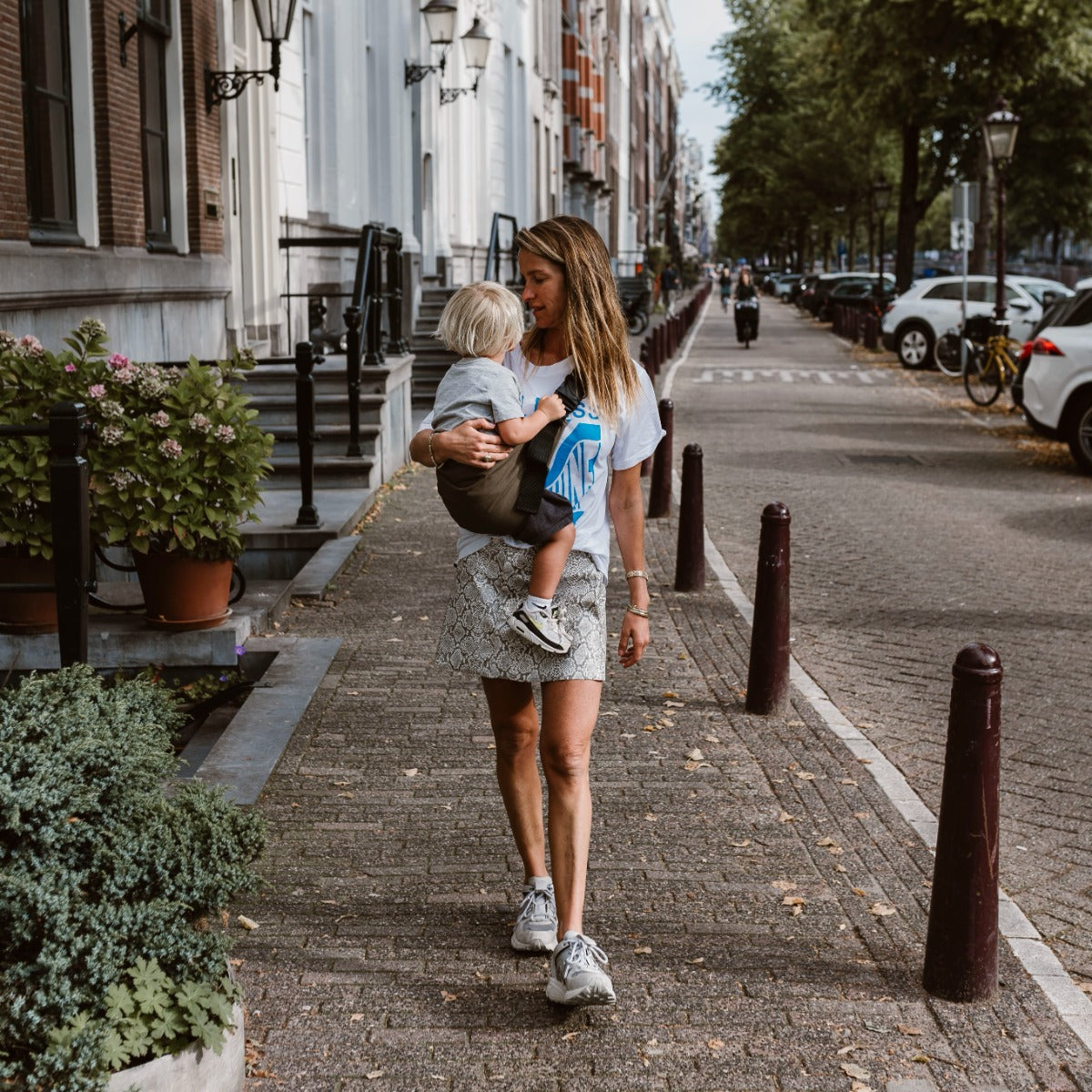 Mother and toddler in town with the Wildride Toddler Carrier in Coffee Colour far shot 