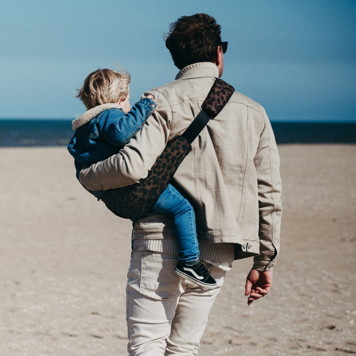 Man holding toddler with Wildride Toddler Carrier Brown Leopard