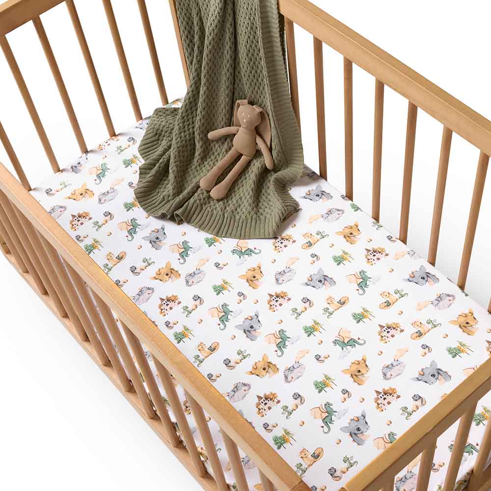 Snuggle Hunny organic cotton cot sheet in dragon print in cot with knit blanket and plush toy