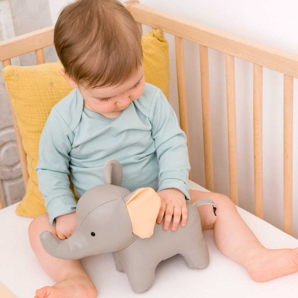 Baby in a cot holding Musical elephant toy in grey from little big friends