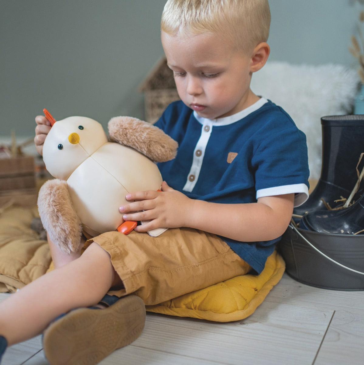 Boy playing with Musical Paulette the Hen toy in beige from little big friends