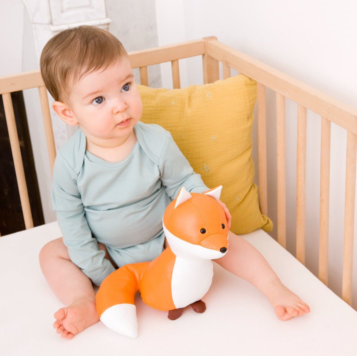 Baby boy holding Little big friends richard the fox musical friend front view in a cot
